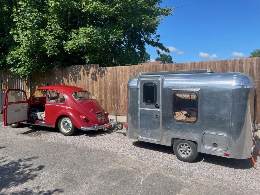 A Red Volkswagen Beetle Decisively Towing A Bluish Metal Trailer