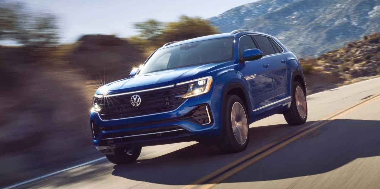 Blue 2026 VW Atlas Cross Sport driving around a curve